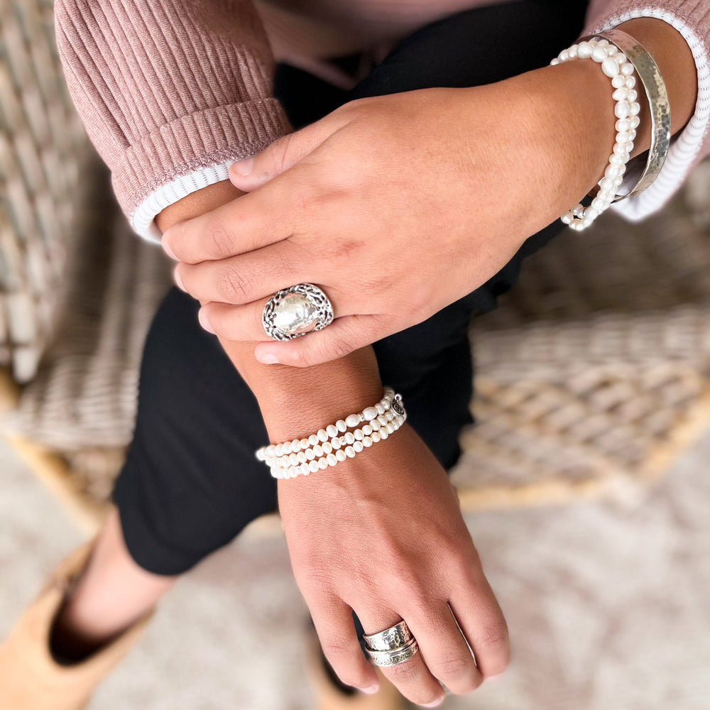 Five bracelets of white freshwater pearls with sterling accent beads are shown on a model. The model is wearing 3 on one wrist and 2 on the other.They are handcrafted in a stretch design to fit nearly everyone.