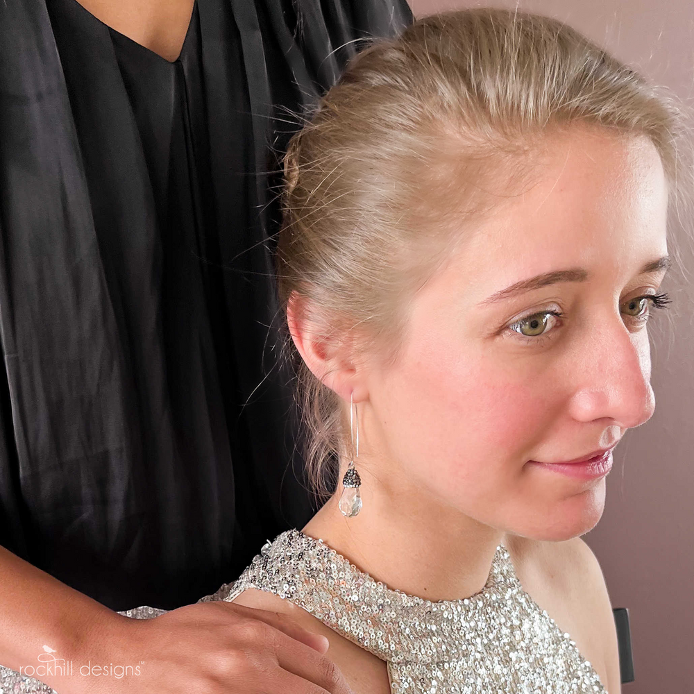 Earrings- faceted crystal teardrops are topped with dainty cut crystals and finished on elongated sterling ear wires. They measure 2 1/4" long and are shown on a model.