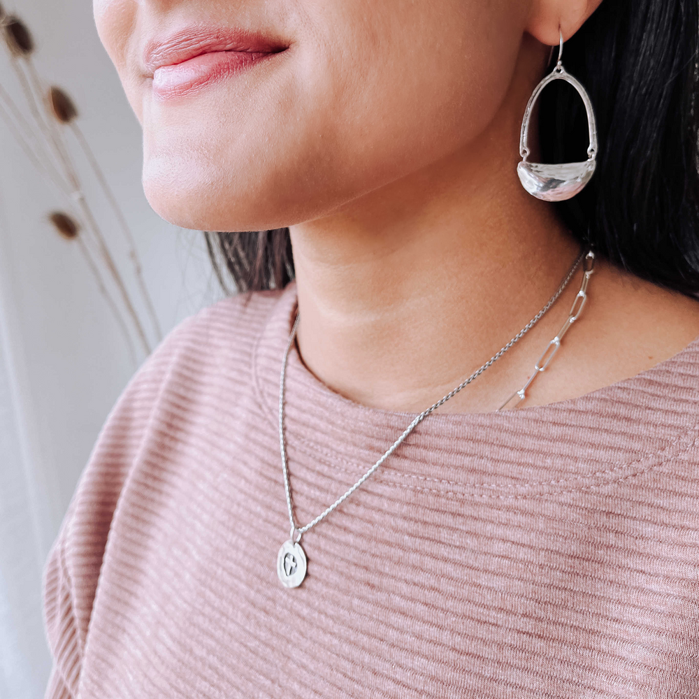 Artisan-crafted sterling silver earrings swing and sway. They measure 2 1/4" long and are shown on a model