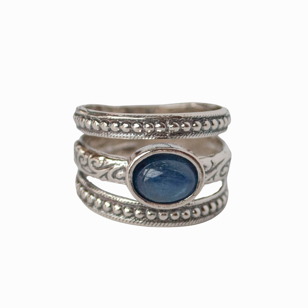 A sterling silver ring with a smooth oval cabochon kyanite stone, featuring intricate designs on the ring face.