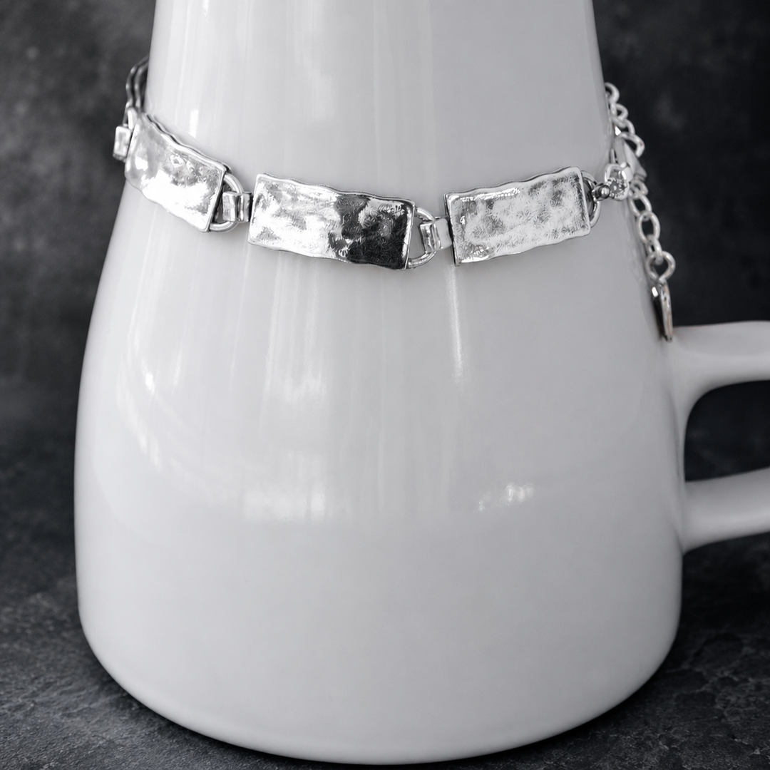 Everyday Sterling Bracelet with hammered rectangular sterling silver links, clasp, extender chain, and RockHill charm displayed around a white ceramic vessel on a dark background.