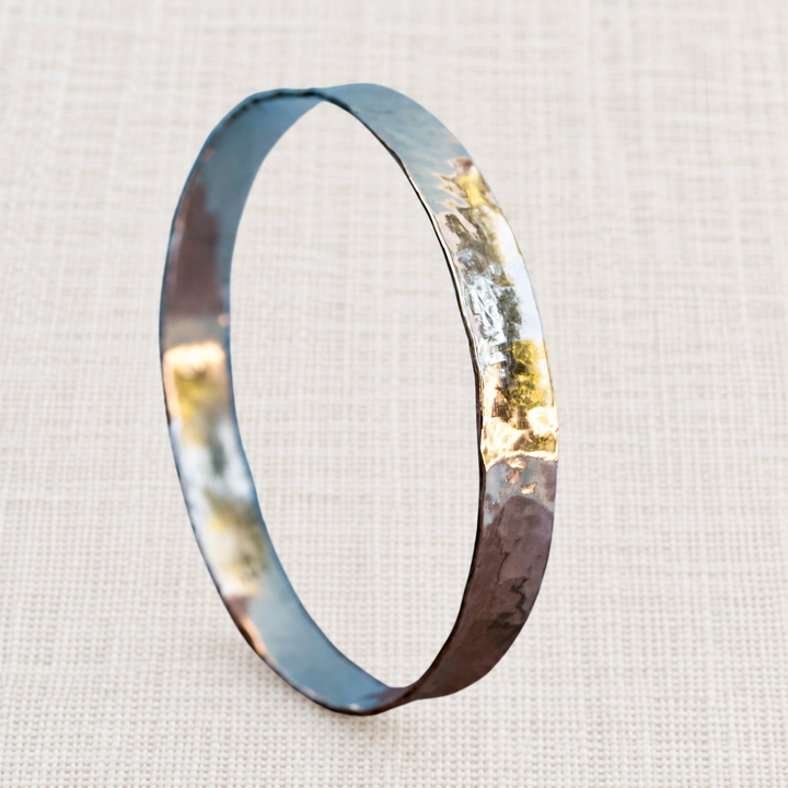 Modern Hammered sterling silver bangle bracelet on a light off-white linen background