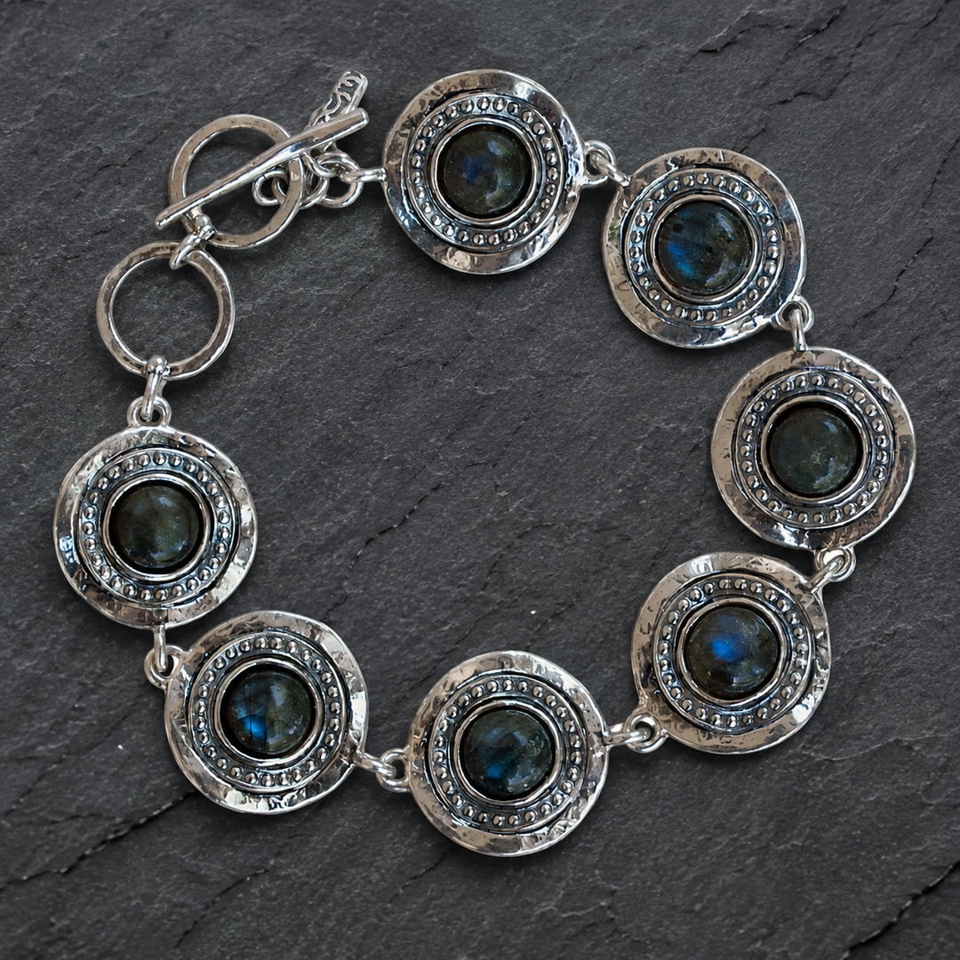 Crowned sterling silver labradorite bracelet with round bezel-set blue labradorite stones styled on a dark slate background.