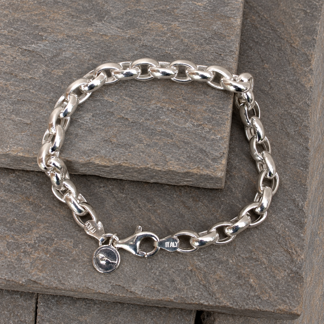 Classic Link Italian sterling silver bracelet with polished oval links, lobster clasp and charm displayed on layered grey-brown slate.
