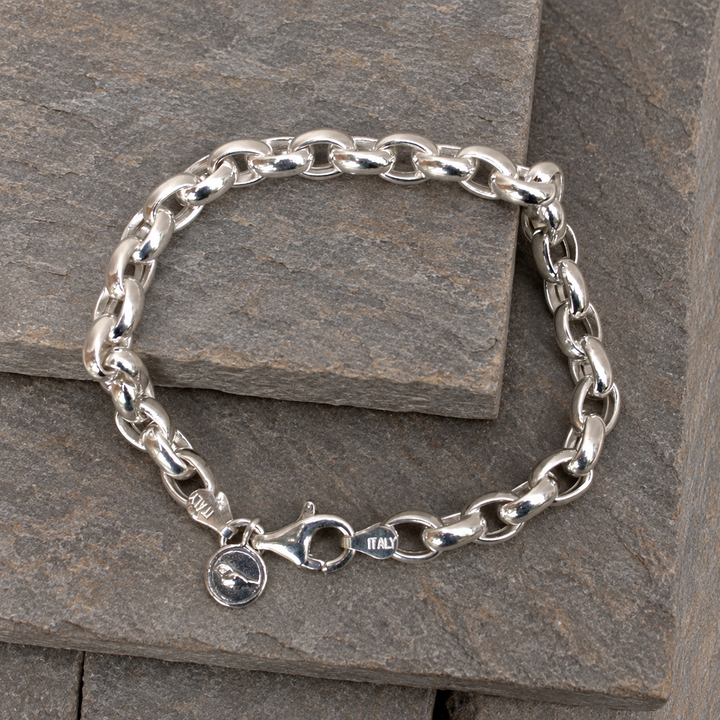 Classic Link Italian sterling silver bracelet with polished oval links, lobster clasp and charm displayed on layered grey-brown slate.