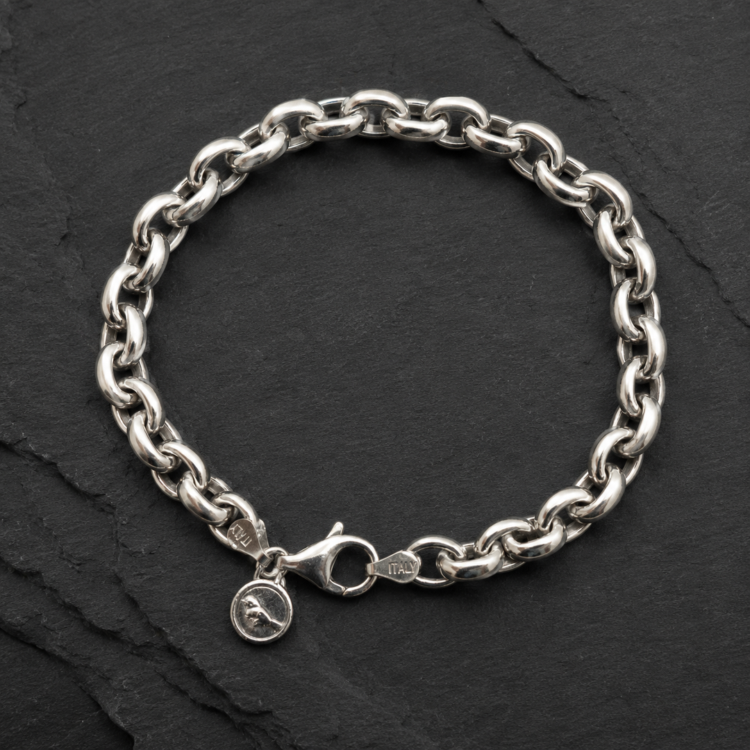Classic Link Bracelet in sterling silver with chunky interlocking links, lobster clasp, and round charm on a dark slate background.