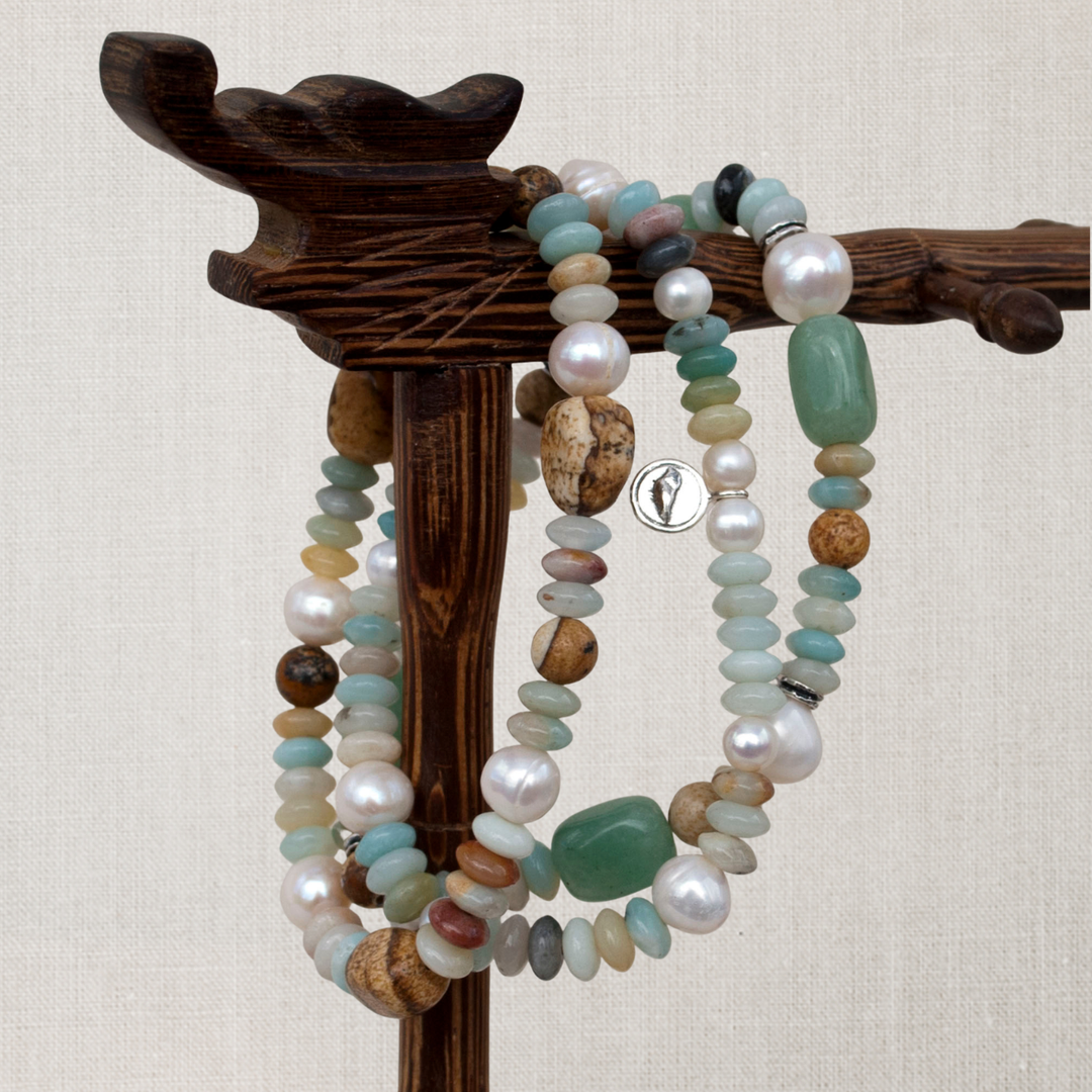Peaceful Palette three-strand stretch bracelet with amazonite, freshwater pearls, picture jasper and sterling silver accents displayed on a dark wood jewelry stand