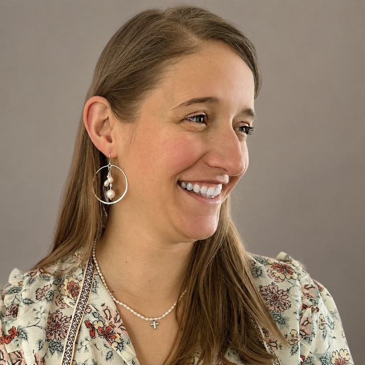 Woman wearing the Graceful Cross Necklace featuring freshwater pearls with a small sterling silver cross pendant.
