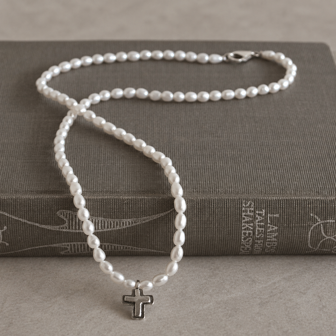 Graceful Cross Necklace with freshwater pearls and sterling silver cross pendant draped over a grey-brown vintage book.