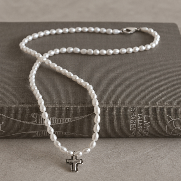 Graceful Cross Necklace with freshwater pearls and sterling silver cross pendant draped over a grey-brown vintage book.