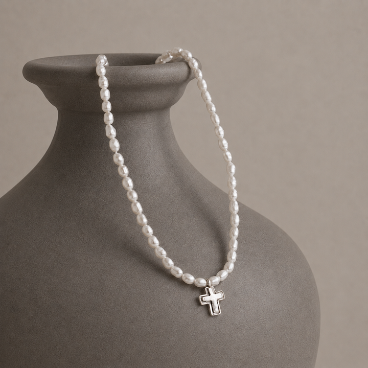 Graceful Cross Necklace with freshwater pearls and sterling silver cross pendant displayed on a grey-brown ceramic vase.