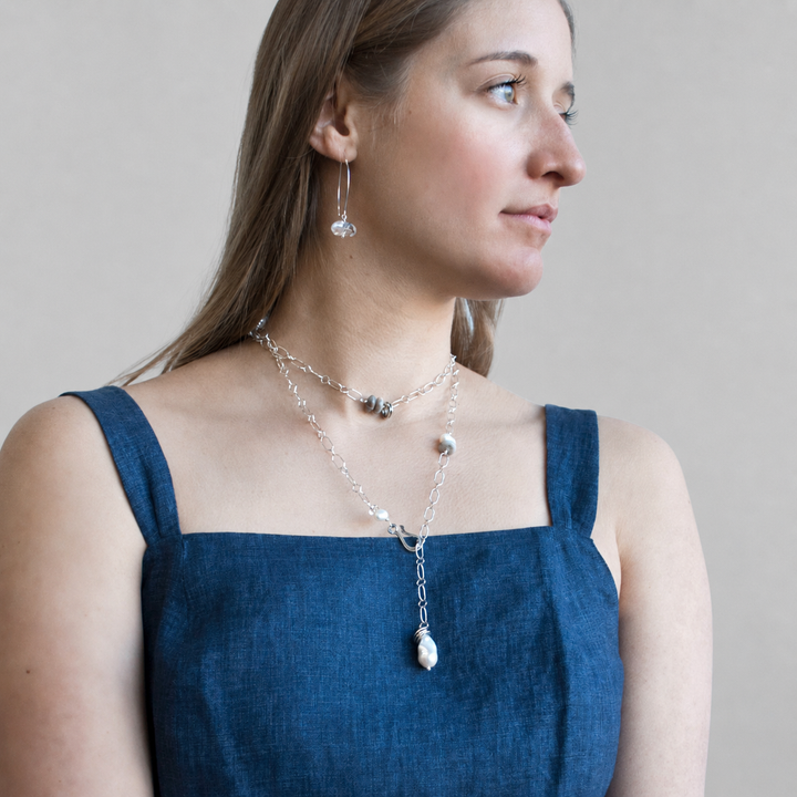 Model wearing the On the Rocks Necklace with sterling silver links, freshwater pearls, gray stones, and clear quartz accents styled as a layered lariat.