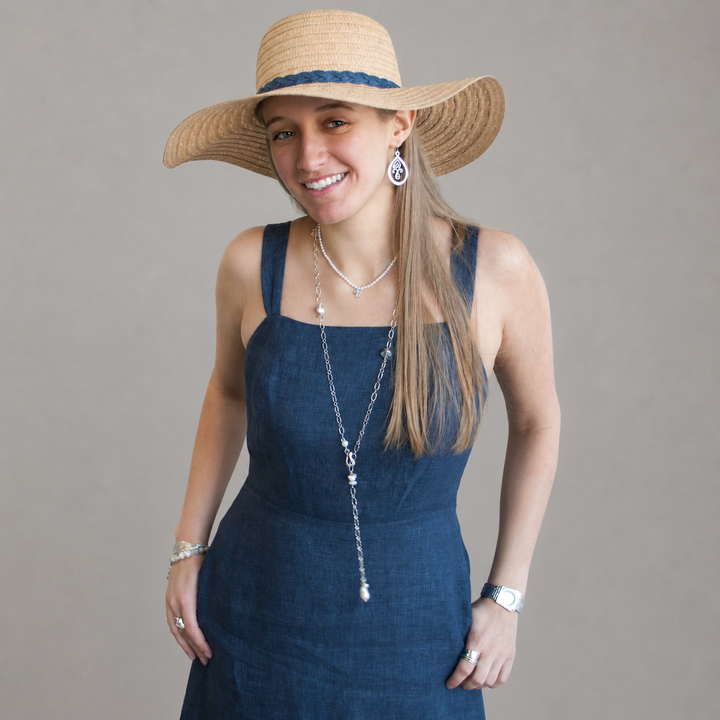 Model wearing the On the Rocks Necklace styled as a long layered lariat with sterling silver links, freshwater pearls, gray stones, and clear quartz accents against a dark gray background.