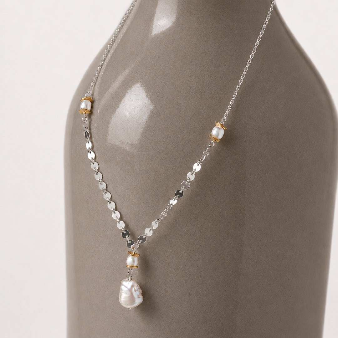 Belle Baroque freshwater pearl necklace with sterling silver chain and gold-plated bead accents displayed on a grey bown ceramic bottle.