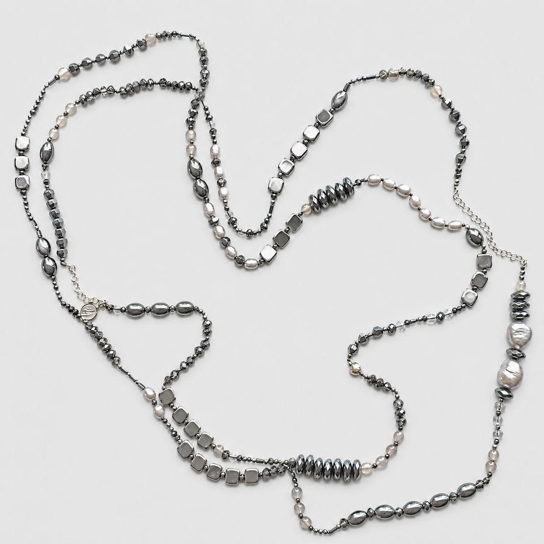 Jet Setter Chic Necklace with hematite, sterling silver, agate, and freshwater pearls arranged in a long layered design on a light neutral background.