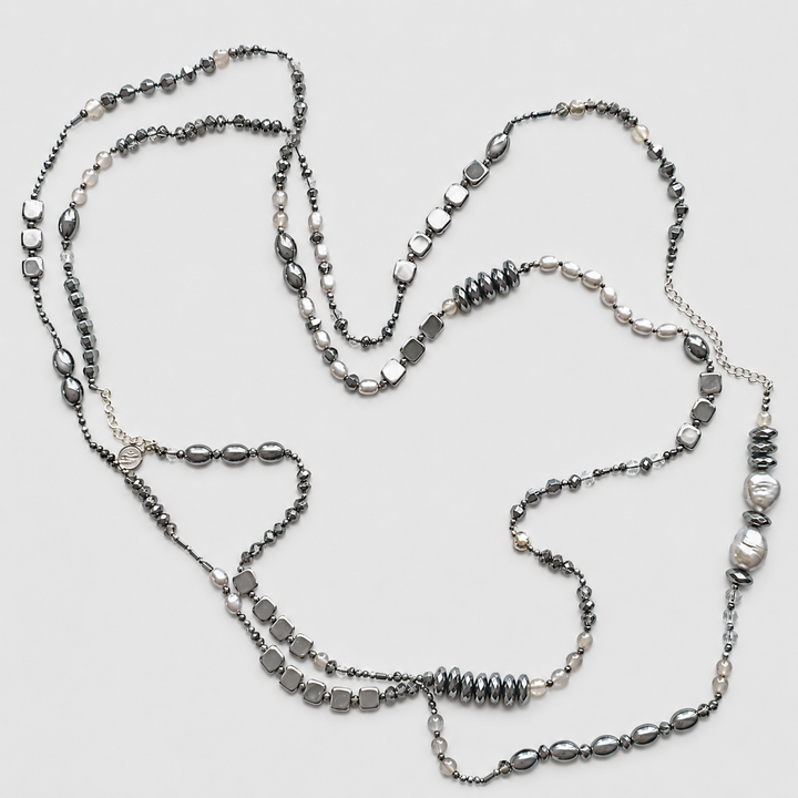 Jet Setter Chic Necklace with hematite, sterling silver, agate, and freshwater pearls arranged in a long layered design on a light neutral background.