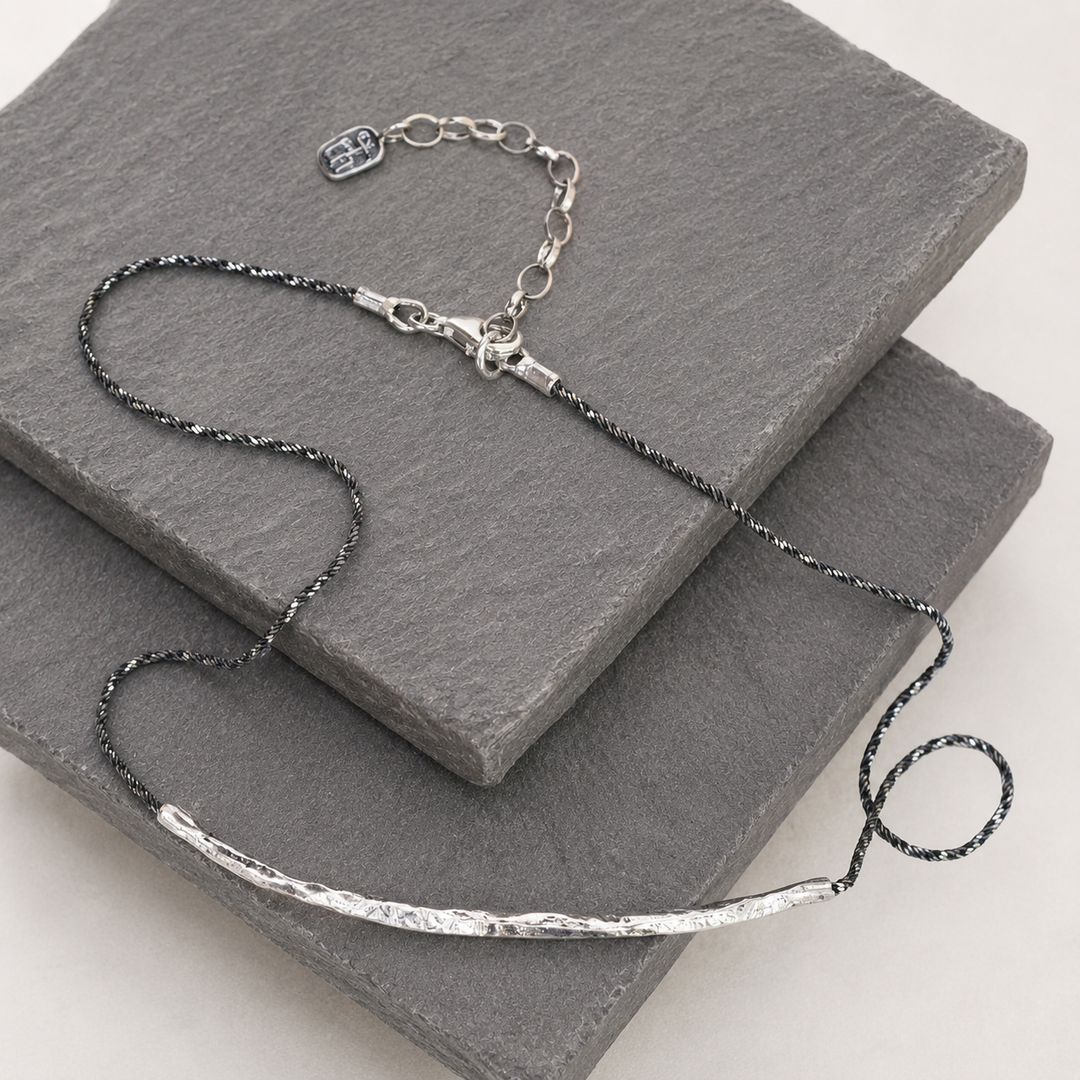 Raise the Bar Necklace with hammered sterling silver bar and dark twisted sterlng silver chain displayed on layered gray slate.