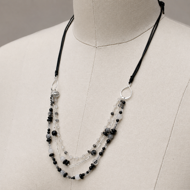 Midnight Harmony multi-strand necklace with black agate, black rutilated quartz, sterling silver and black leather displayed on an off white jewelry bust.