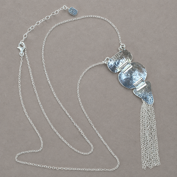 Meadowland Necklace N398, long sterling silver necklace with textured geometric pendant and chain tassel arranged on a soft gray-brown background.