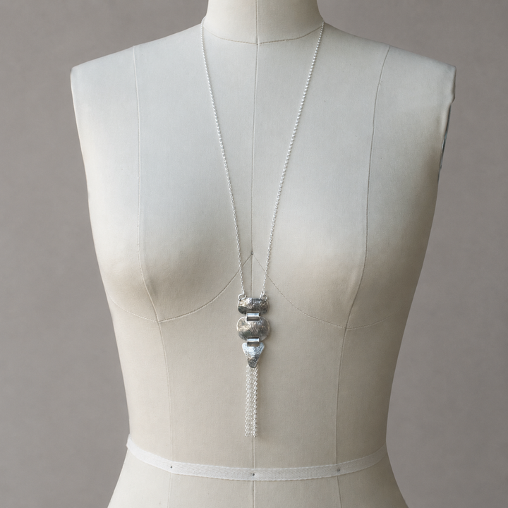Meadowland Necklace N398, long sterling silver textured pendant necklace with chain tassel displayed on a neutral dress form.