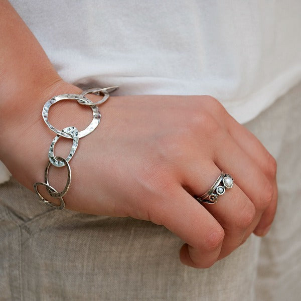 A sterling silver ring with three freshwater pearls set in a band with ornate details. Shown pn a model.