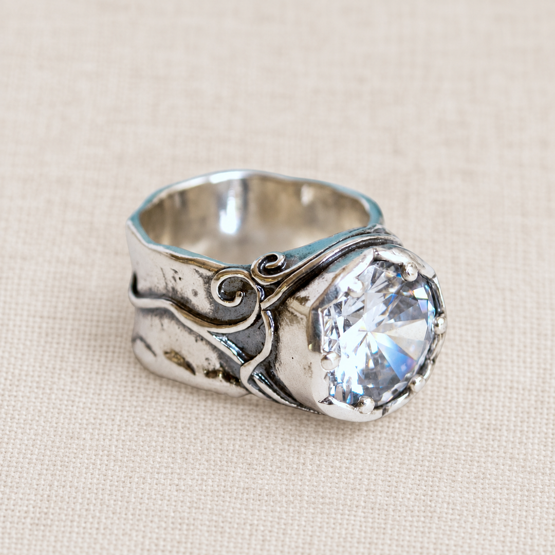 Bombshell sterling silver ring with large clear CZ, artisan-crafted of .925 sterling silver, is shown on a light linen background. 