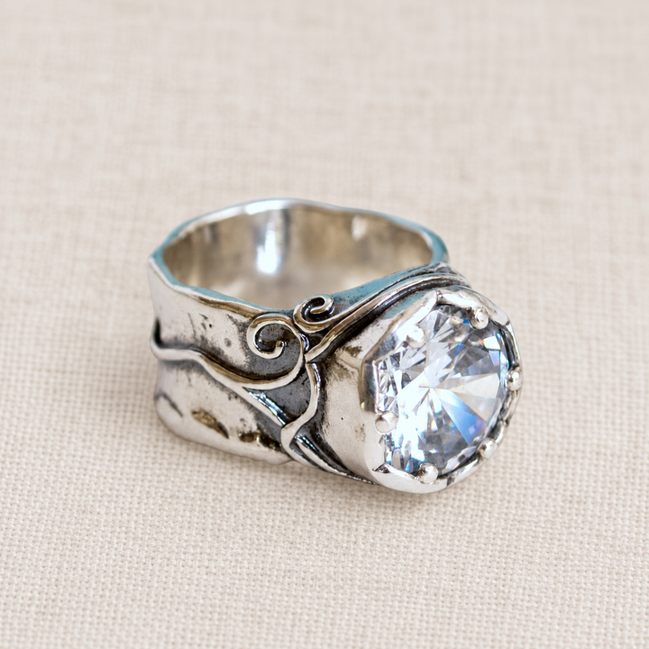 Bombshell sterling silver ring with large clear CZ, artisan-crafted of .925 sterling silver, is shown on a light linen background. 