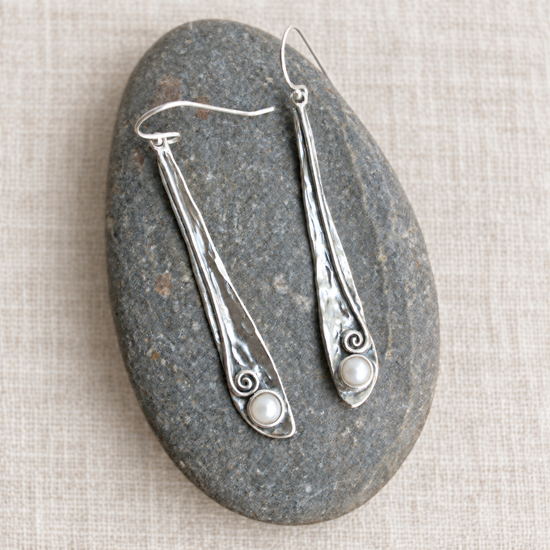 Pearly Vine Earrings with hammered sterling silver and freshwater pearls displayed on a smooth grey stone over light off-white linen