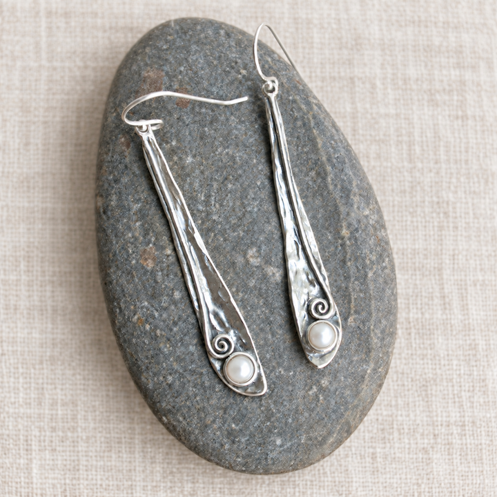 Pearly Vine Earrings with hammered sterling silver and freshwater pearls displayed on a smooth grey stone over light off-white linen