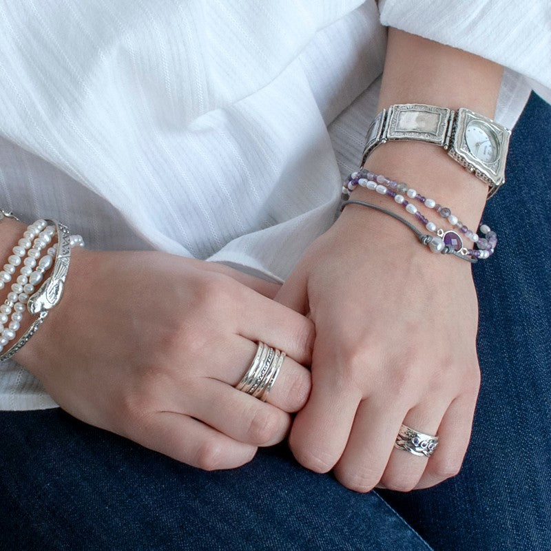 A mixed gemstone bracelet with tiers of freshwater pearls, amethyst, and iolite, featuring leather and a sterling lobster clasp, shown on a model.
