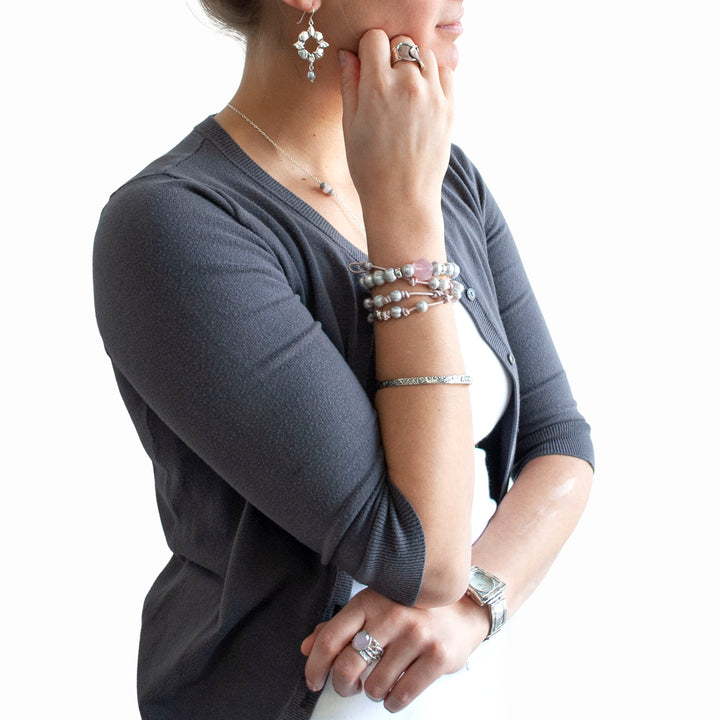 Knotted light pink leather, accented with the soft glow of cultured freshwater pearls in grey, wraps around your wrist three times in this artisan-crafted bracelet. Shown on a model with a white beckground. 