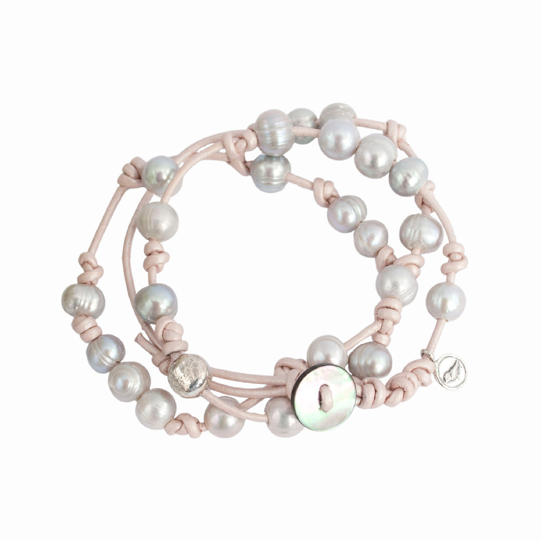 Knotted light pink leather, accented with the soft glow of cultured freshwater pearls in grey, wraps around your wrist three times in this artisan-crafted bracelet. Shown on a white background. 