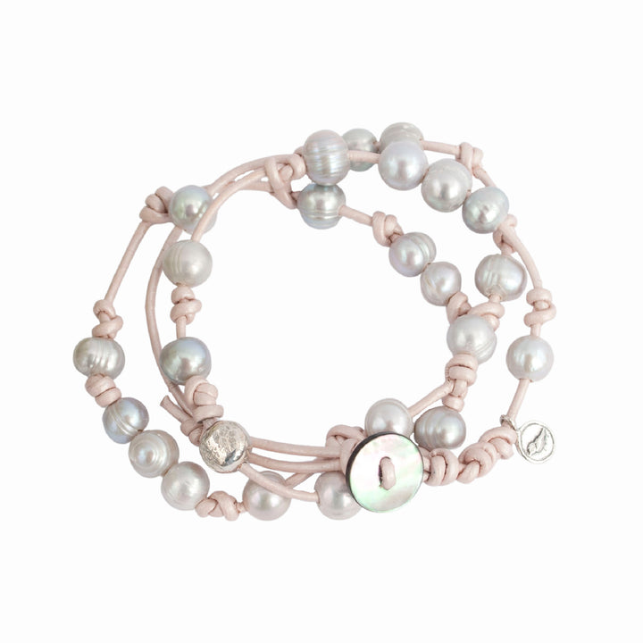 Knotted light pink leather, accented with the soft glow of cultured freshwater pearls in grey, wraps around your wrist three times in this artisan-crafted bracelet. Shown on a white background. 