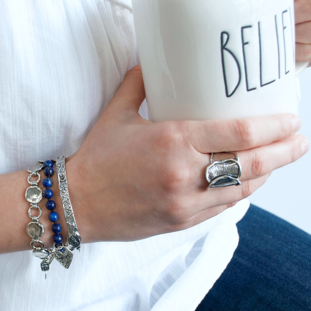 A sterling silver link bracelet with a textured finish and an adjustable toggle closure. Shown on a model.