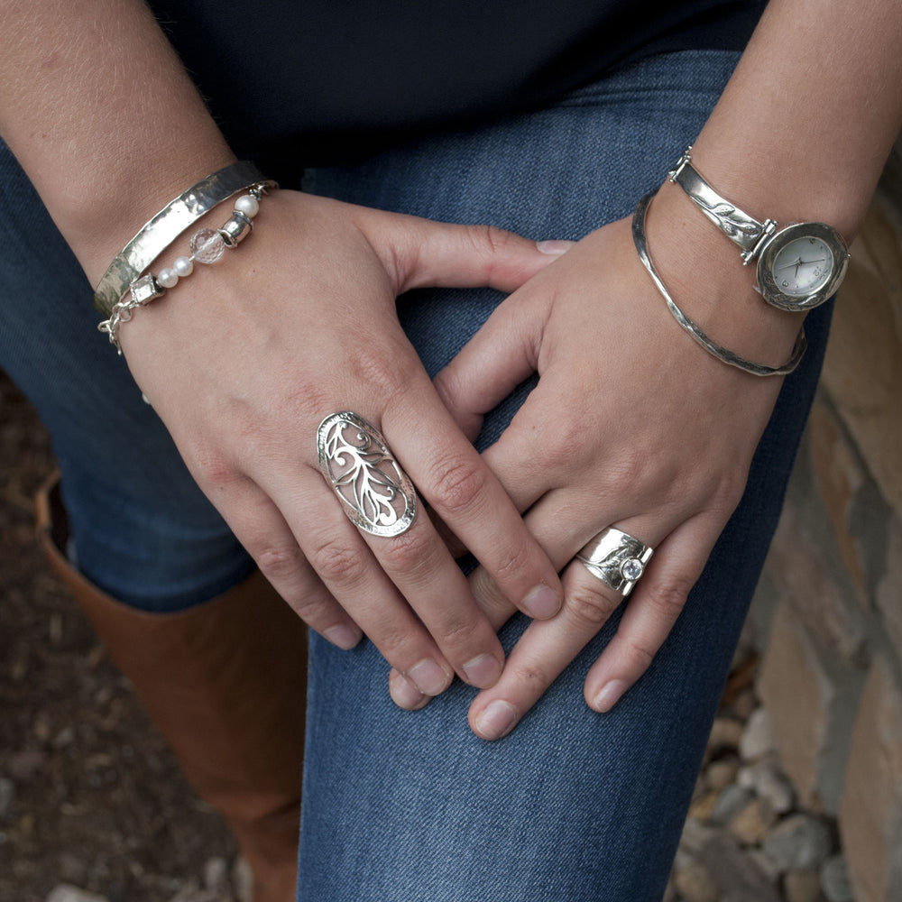 A sterling silver link bracelet with white freshwater pearls, faceted clear quartz, and silver accents is shown on a model.
