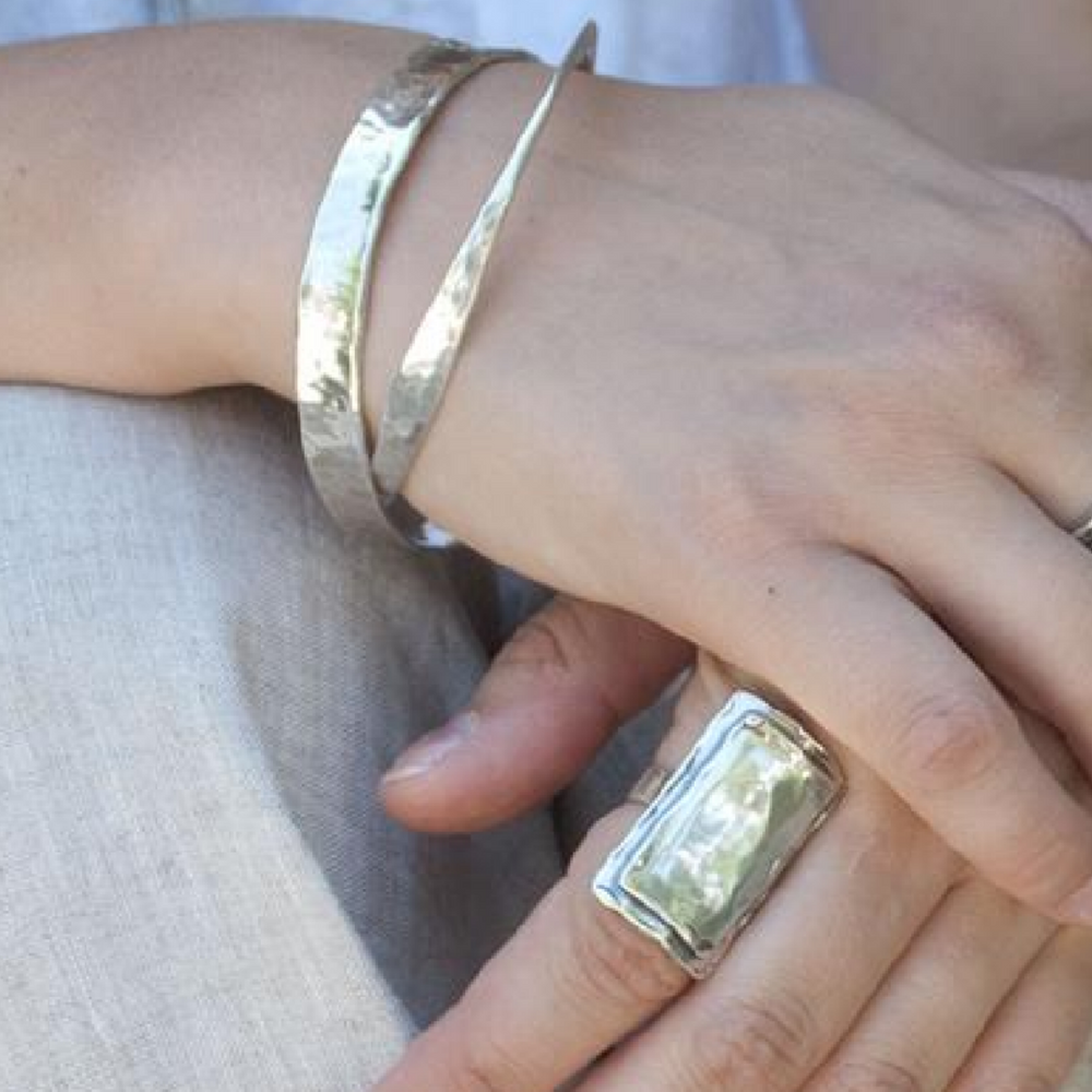 Hammered sterling silver, .925 bangle bracelet shown on a model with a smaller bangle and rectangular sterling silver ring.