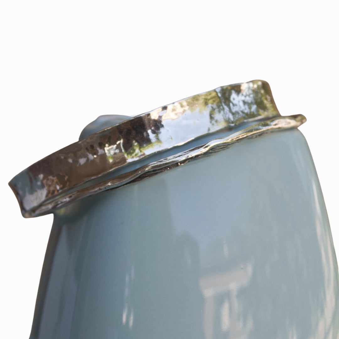 A sterling silver bangle bracelet, artisan-crafted in a hammered design for adding a hint of modern detail and dimension to any outfit. Shown on a blue ceramic piece. 