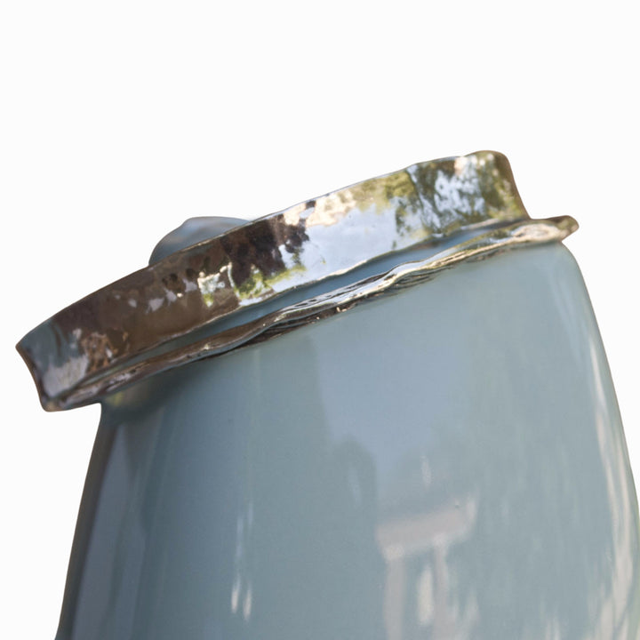 A sterling silver bangle bracelet, artisan-crafted in a hammered design for adding a hint of modern detail and dimension to any outfit. Shown on a blue ceramic piece. 