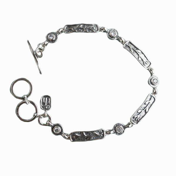 A single-strand sterling silver bracelet with bezel-set faceted clear CZs and an adjustable toggle closure. Shown on a white background. 