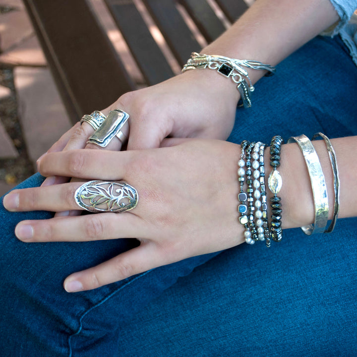 Multi-strand bracelet- crafted with grey freshwater pearl, a variety of hematite, and crystal. Finished with a .925 sterling silver bar clasp. Available in sizes small, medium, and large. Shown on a model.