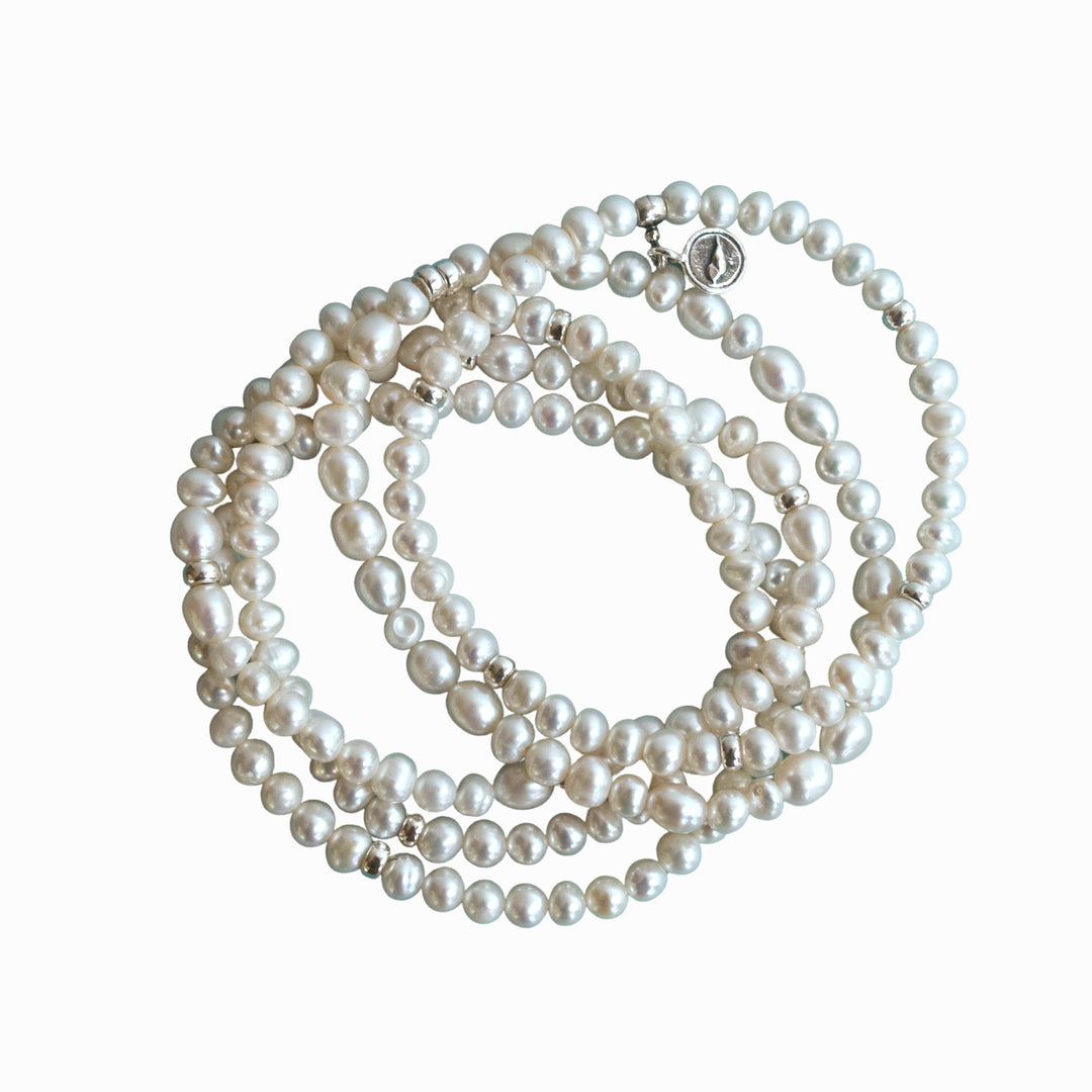Five bracelets of white freshwater pearls with sterling accent beads are shown on a white background. They are handcrafted in a stretch design to fit nearly everyone.