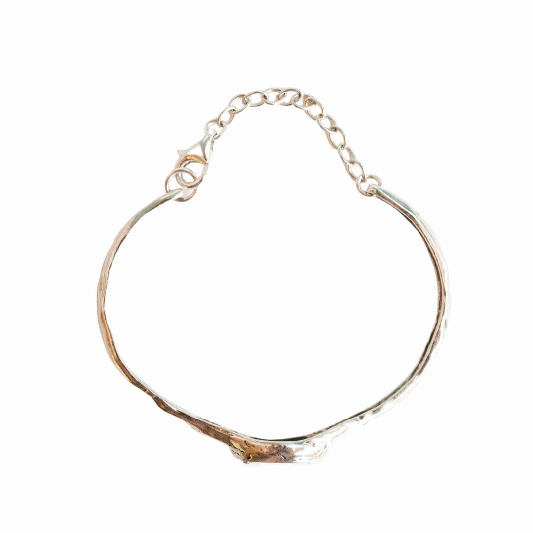 Silver Bracelet with a beautiful oval faceted clear CZ. Cuff-style bracelet with a safety chain. Artisan-crafted sterling silver bracelet. Alternative view shown from above.