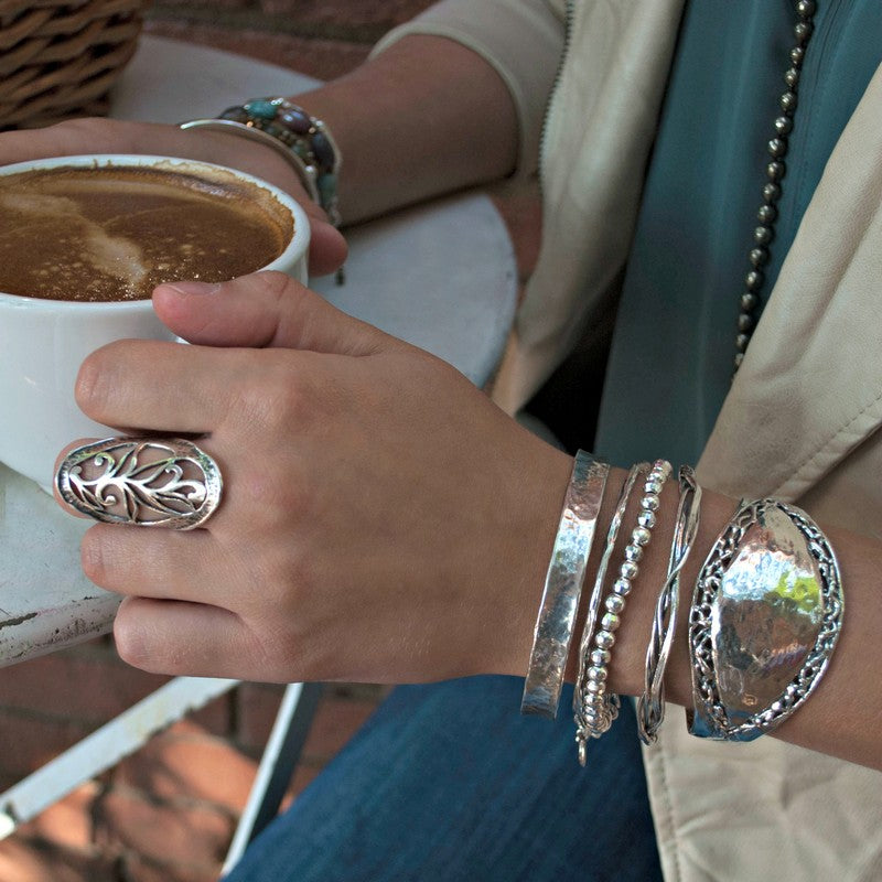 A sterling silver cuff bracelet with a hammered finish and filigree border,shown on a model. 