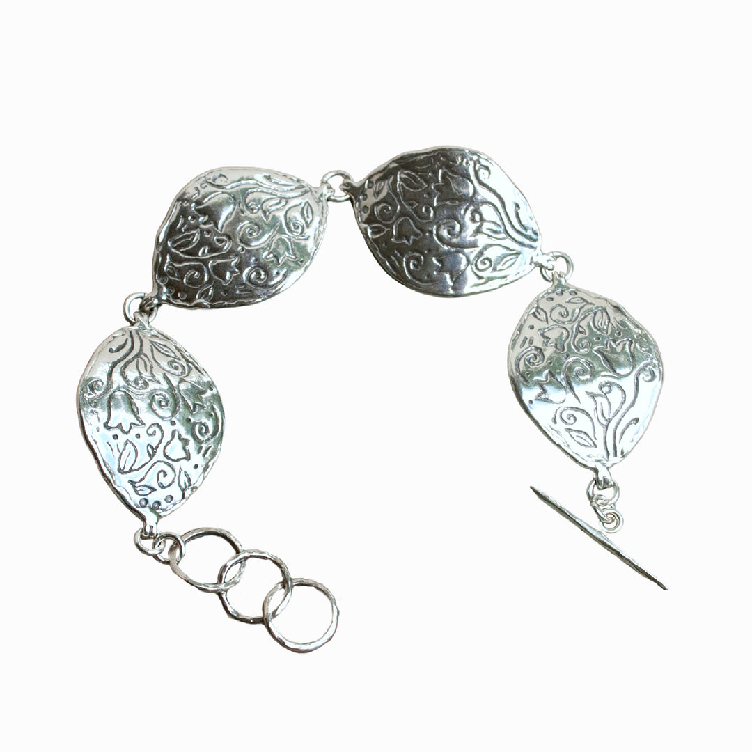 A sterling silver bracelet with a floral pattern, featuring four curved pieces and an adjustable toggle clasp. Shown on a white background.