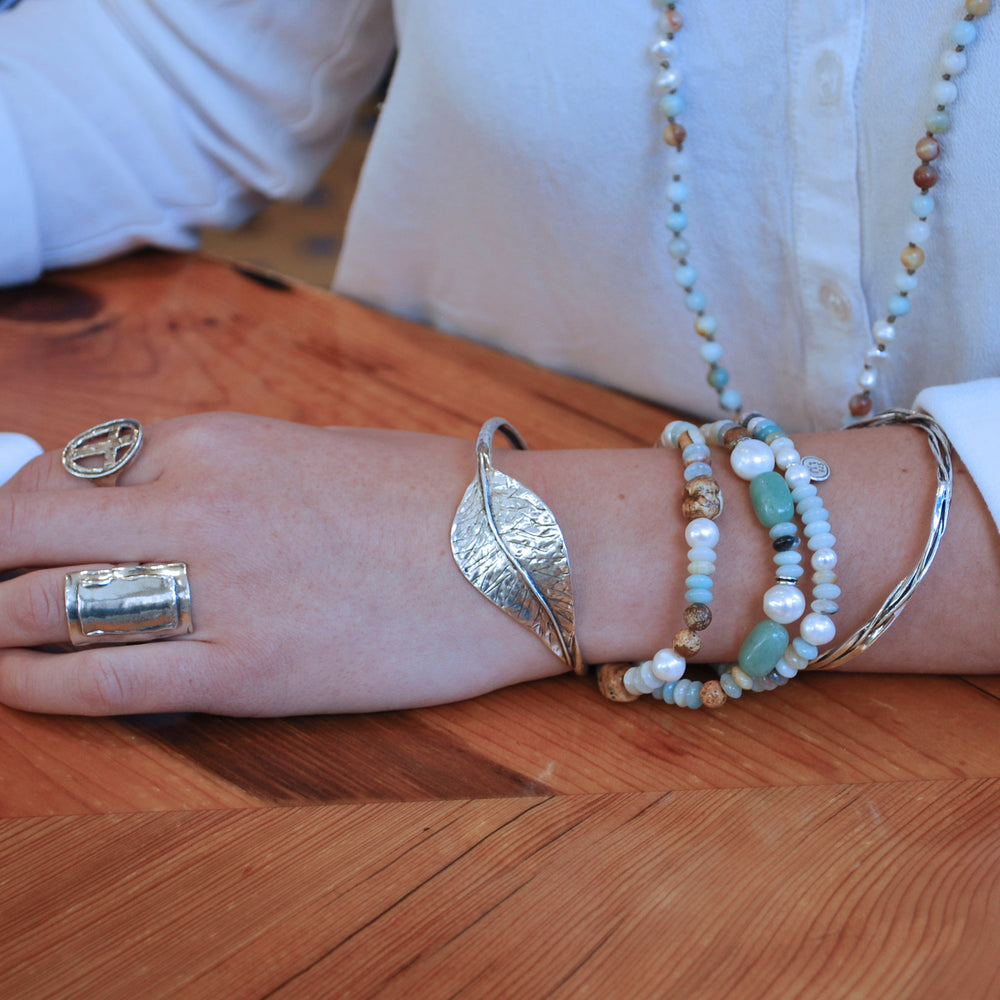 A sterling silver leaf cuff bracelet shown on a model. 