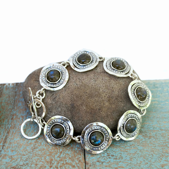 A bracelet with Labradorite cabochons,  set in sterling silver frames, connected by sterling silver links, with an adjustable toggle closure. Shown on a grey stone. 