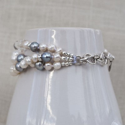 A multi-strand pearl bracelet with clear quartz and sterling silver accents, toggle view displayed on white ceramic. 