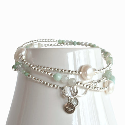 Convertible Necklace- wear as a wrap bracelet or necklace. Crafted of white freshwater pearls, aquamarine, amazonite and .925 sterling silver. Shown as a bracelet on white mug.
