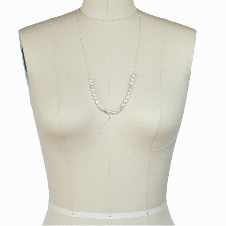 Pearl with Sterling accent beads necklace is shown on a dress from in its longest length.