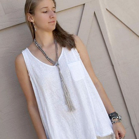 A lariat necklace with peacock freshwater pearls, grey agate, and grey cord, featuring long variegated tassels, is shown worn as a lariat on a model. 